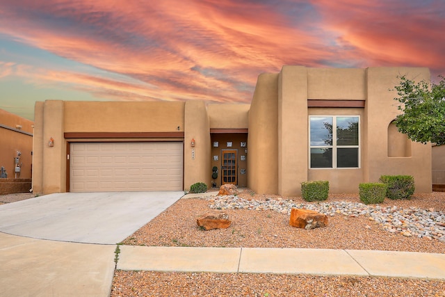 southwest-style home featuring a garage, concrete driveway, and stucco siding