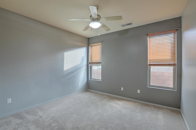 carpeted empty room with visible vents, baseboards, and a ceiling fan