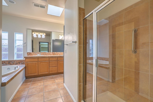 bathroom featuring visible vents, a shower stall, a garden tub, a skylight, and vanity