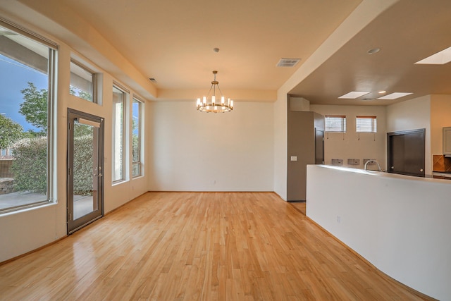 interior space with an inviting chandelier, light wood-style flooring, and visible vents