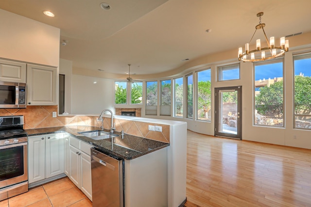 kitchen with a healthy amount of sunlight, decorative backsplash, a peninsula, stainless steel appliances, and a sink