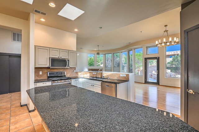 kitchen featuring a sink, visible vents, appliances with stainless steel finishes, and a peninsula