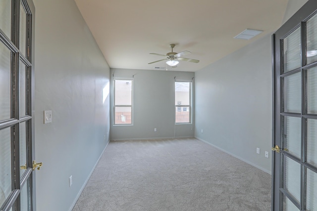 empty room featuring a ceiling fan, visible vents, carpet, and baseboards