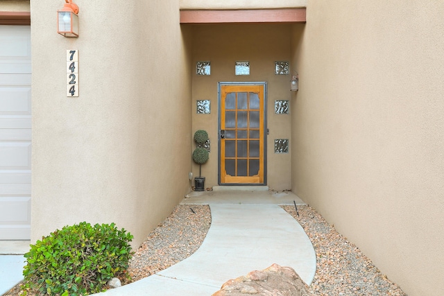 property entrance with a garage and stucco siding