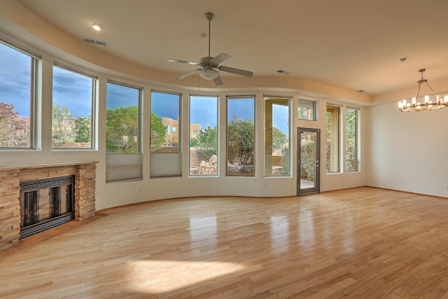 unfurnished living room with light wood finished floors, visible vents, plenty of natural light, and a stone fireplace