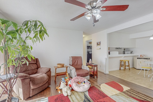 living room featuring washer / clothes dryer, light hardwood / wood-style flooring, ceiling fan, and a textured ceiling