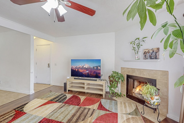 living room featuring a fireplace, hardwood / wood-style floors, and ceiling fan