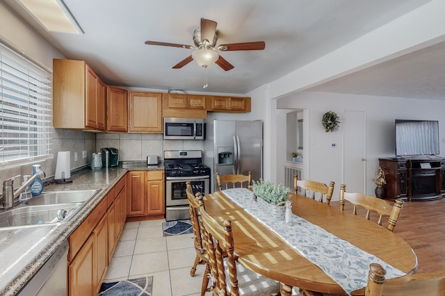 kitchen featuring ceiling fan, backsplash, light tile patterned flooring, sink, and stainless steel appliances