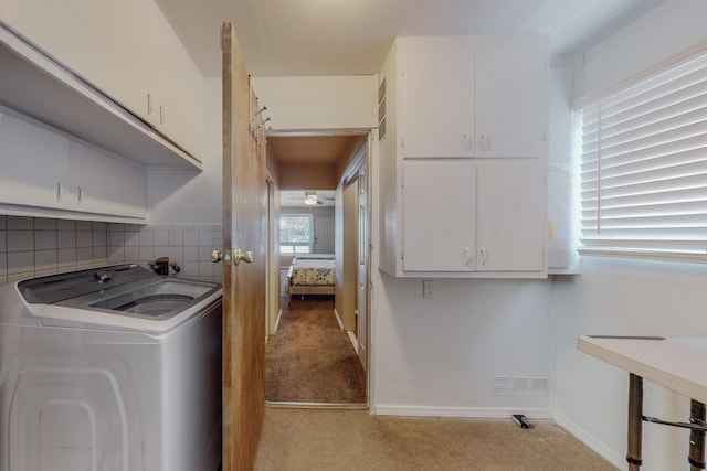 clothes washing area with washer / dryer, cabinets, and light colored carpet