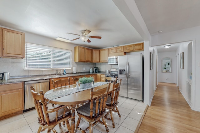 kitchen featuring backsplash, sink, appliances with stainless steel finishes, light hardwood / wood-style floors, and ceiling fan