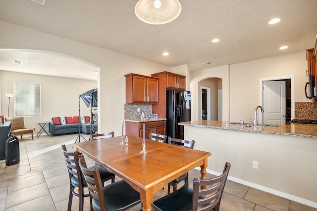 dining space with a textured ceiling, light tile patterned floors, and sink