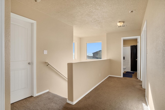 hall featuring a textured ceiling and carpet floors