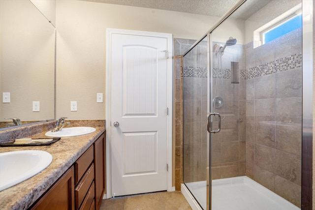 bathroom featuring vanity, a shower with shower door, and a textured ceiling