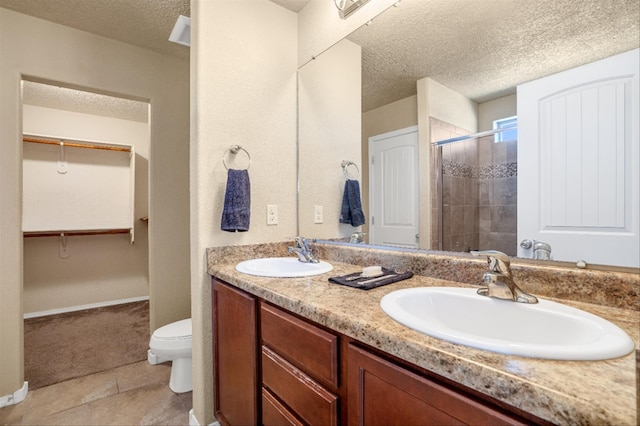 bathroom with tile patterned floors, vanity, a textured ceiling, and walk in shower