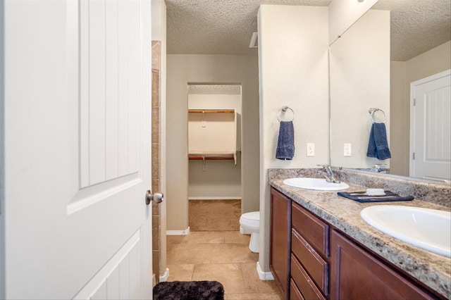 bathroom featuring tile patterned flooring, vanity, a textured ceiling, and toilet