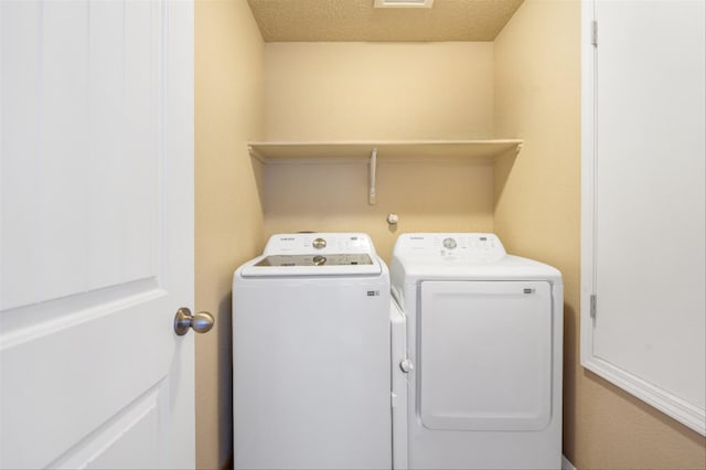 laundry room with a textured ceiling and separate washer and dryer