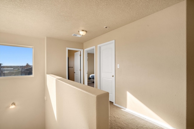 corridor featuring carpet and a textured ceiling