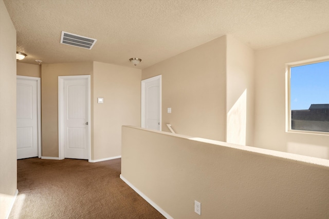 corridor with carpet floors and a textured ceiling