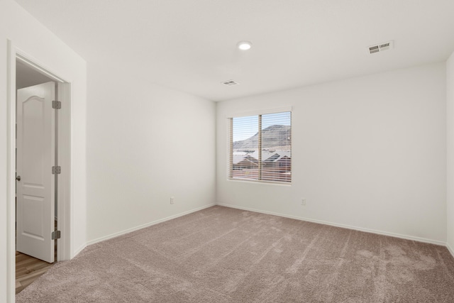 spare room featuring light carpet, baseboards, visible vents, and recessed lighting