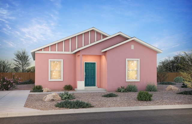 view of front of home featuring fence, board and batten siding, and stucco siding