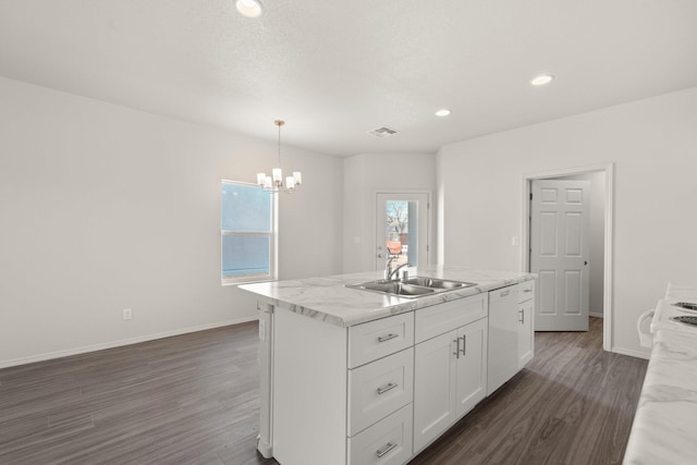 kitchen featuring white dishwasher, a kitchen island with sink, a sink, white cabinetry, and decorative light fixtures