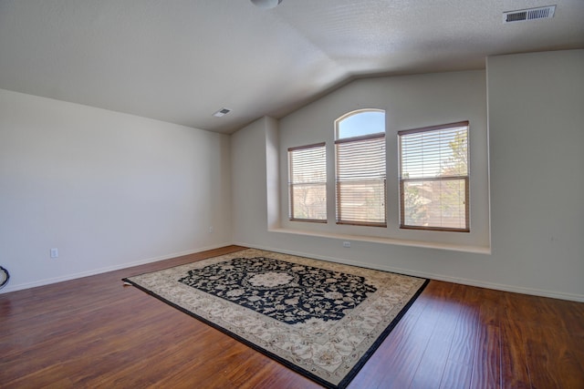 interior space with a textured ceiling, lofted ceiling, and dark hardwood / wood-style floors