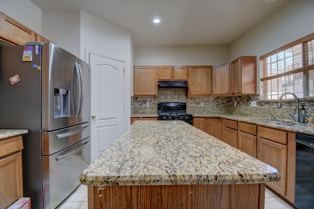 kitchen featuring light stone counters, backsplash, black appliances, a center island, and sink