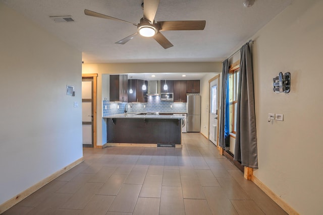 kitchen with visible vents, backsplash, appliances with stainless steel finishes, a peninsula, and a kitchen breakfast bar