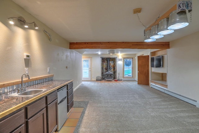 kitchen with a baseboard radiator, light colored carpet, a sink, open floor plan, and a wood stove