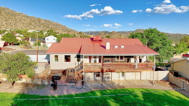 back of property featuring a patio, a lawn, stairway, metal roof, and a mountain view