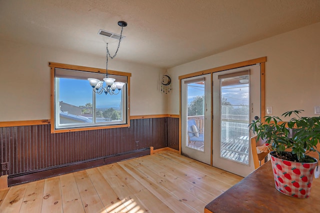 unfurnished dining area with a healthy amount of sunlight, a baseboard radiator, visible vents, and wainscoting