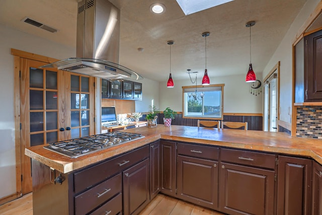 kitchen with hanging light fixtures, visible vents, island exhaust hood, and stainless steel gas cooktop