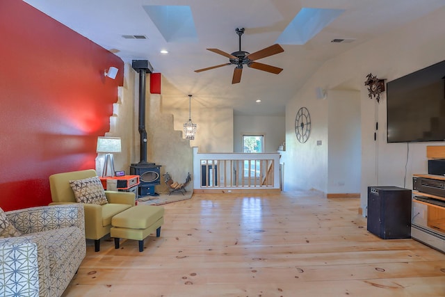 living area with a wood stove, wood-type flooring, and visible vents