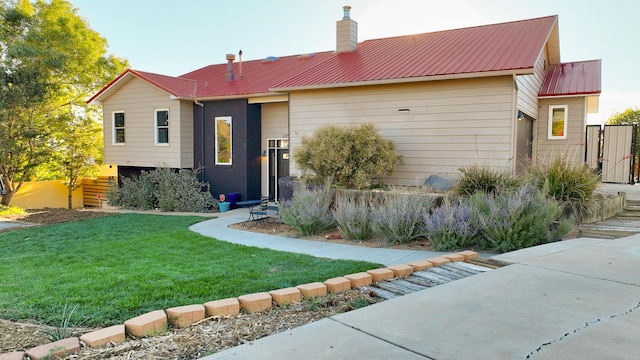 view of front of home featuring metal roof, a chimney, and a front lawn