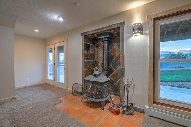 entryway featuring a wood stove, carpet flooring, plenty of natural light, and baseboard heating