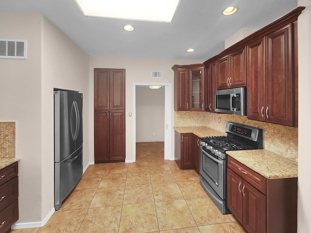 kitchen with light stone counters, stainless steel appliances, and decorative backsplash