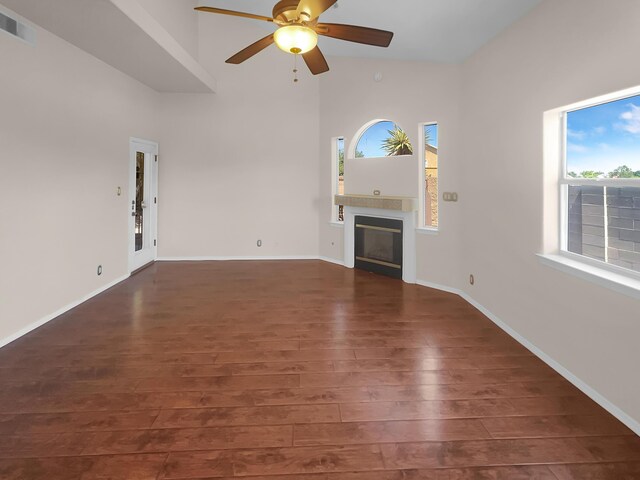 unfurnished living room featuring wood-type flooring, a high ceiling, and ceiling fan