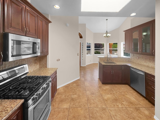 kitchen featuring appliances with stainless steel finishes, glass insert cabinets, light stone counters, and a sink