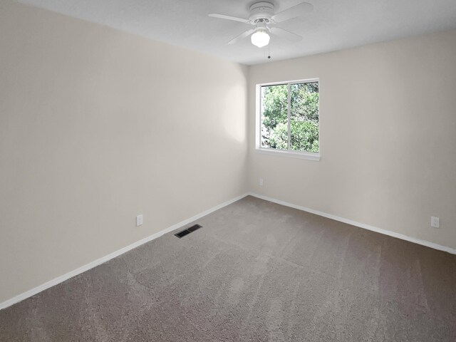 carpeted spare room with a ceiling fan, visible vents, and baseboards