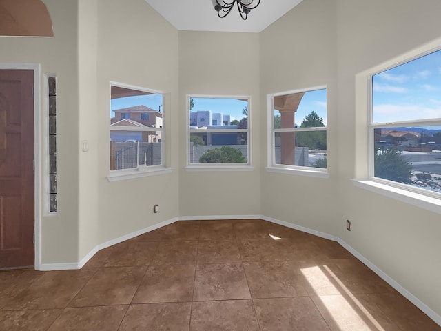 interior space with tile patterned flooring, a towering ceiling, and baseboards