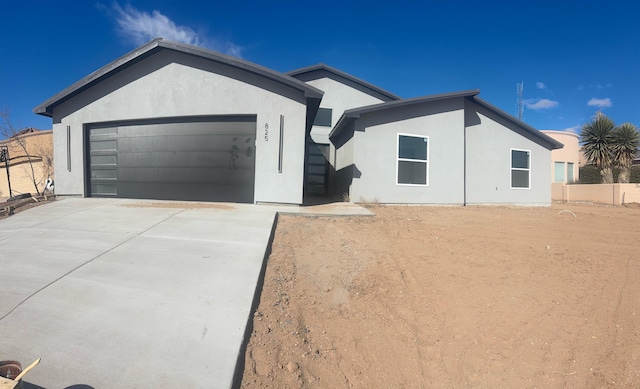 ranch-style home featuring stucco siding, a garage, driveway, and fence