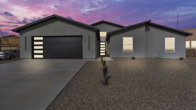 view of front of property with stucco siding, an attached garage, and concrete driveway