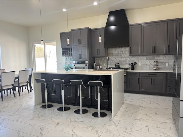 kitchen featuring oven, wall chimney range hood, light countertops, decorative backsplash, and marble finish floor