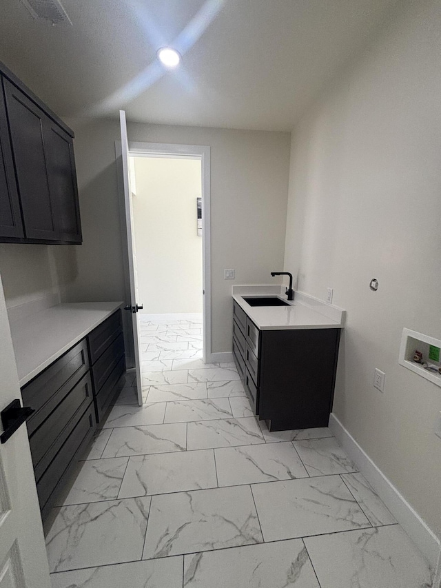 interior space featuring baseboards, hookup for a washing machine, cabinet space, marble finish floor, and a sink