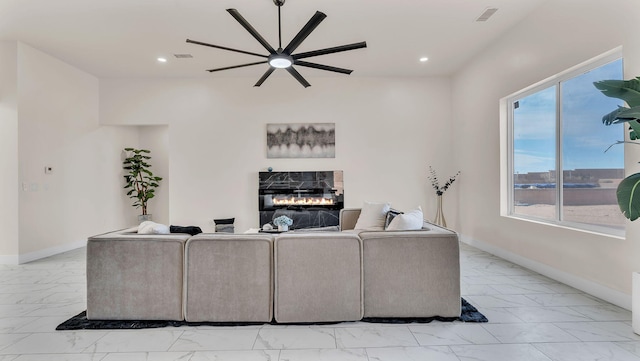 living area featuring baseboards, marble finish floor, ceiling fan, recessed lighting, and a glass covered fireplace