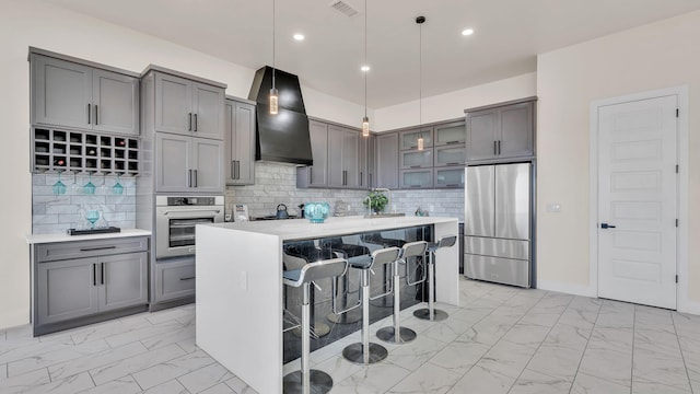 kitchen featuring wall chimney range hood, marble finish floor, appliances with stainless steel finishes, and gray cabinets