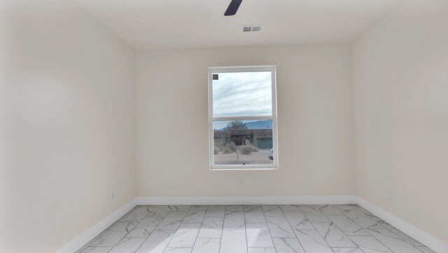 empty room with baseboards, marble finish floor, ceiling fan, and visible vents