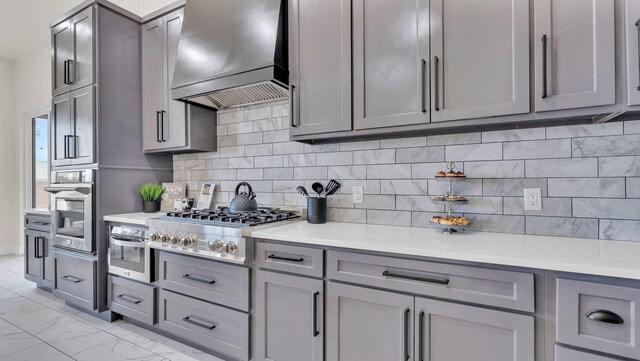 kitchen featuring custom range hood, a warming drawer, stainless steel appliances, and gray cabinetry