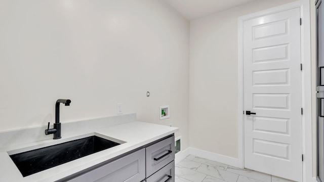 clothes washing area with baseboards, marble finish floor, a sink, cabinet space, and washer hookup