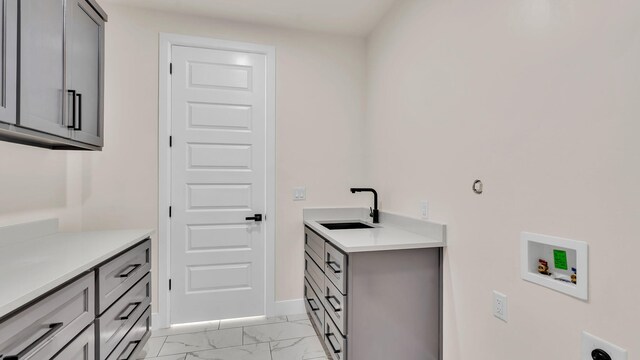 clothes washing area featuring hookup for a washing machine, baseboards, marble finish floor, a sink, and cabinet space